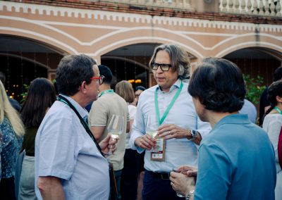 Three DNSG 2026 attendees talking over drinks during the outdoor symposium reception.