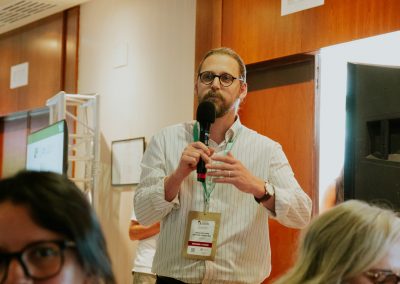 Attendee standing and contributing to a scientific discussion with a handheld microphone.