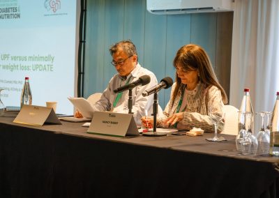 Two session chairs reviewing their notes at the panel table during a DNSG 2026 scientific session