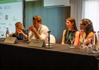 Speaker addressing the audience from a panel table alongside other DNSG 2026 participants.
