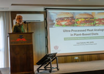 Speaker presenting research on ultra-processed meat alternatives and plant-based diets at DNSG 2026.