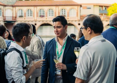 Three DNSG 2026 attendees talking and sharing drinks during an outdoor networking reception.