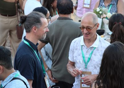 Two DNSG 2026 attendees smiling and talking over drinks during the outdoor reception.